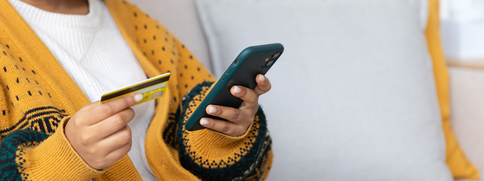 Naisoletettu pitää kädessään pankkikorttia ja mobiililaitetta